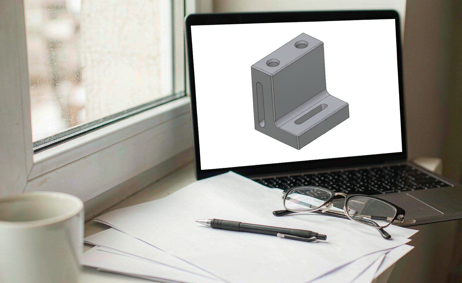 Printed confidentiality agreement beside a laptop showing a CAD model